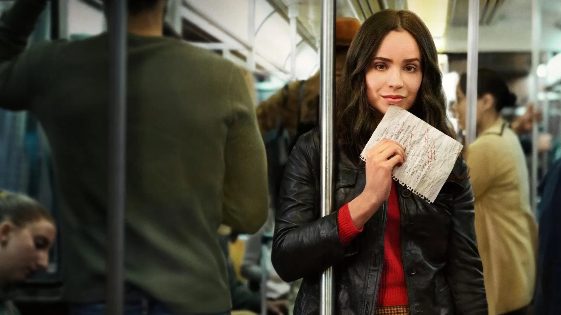 Woman on a subway train holding a crumpled list, looking directly at the viewer, from The Life List movie.
