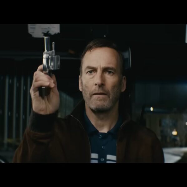 Bob Odenkirk as Hutch Mansell holding a small handgun on a public bus, confronting a group of assailants in a pivotal fight scene from the movie Nobody.