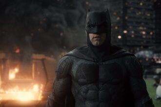 Ben Affleck's Batman in a dark, gritty scene with fire and destruction, embodying action and drama, not horror.