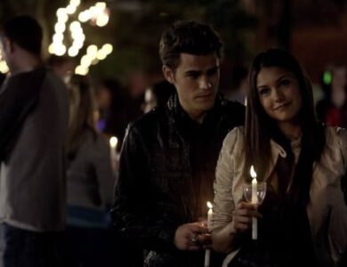 Stefan Salvatore and Elena Gilbert holding candles at the outdoor comet viewing event in Mystic Falls.