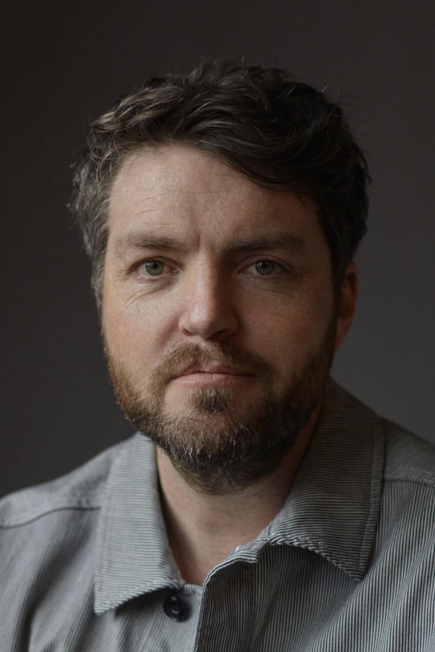 A headshot of Tom Burke.