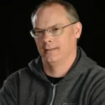 Headshot of CEO of EPIC GAMES Tim Sweeney on a dark background.